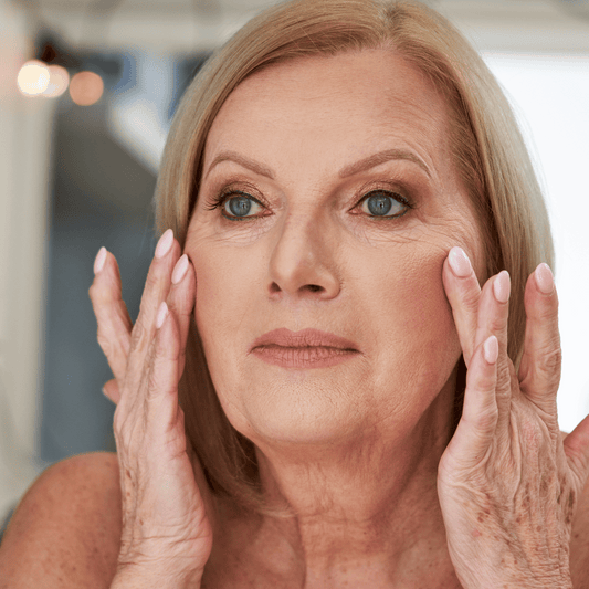 a middle aged blonde woman looking herself in the mirrow and touching her face with her fingers