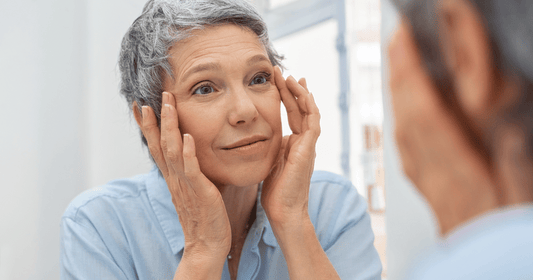 A woman with grey pixie cut looking herself in the mirrow.