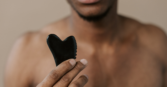A man holding black obsidian gua sha tool on his hand