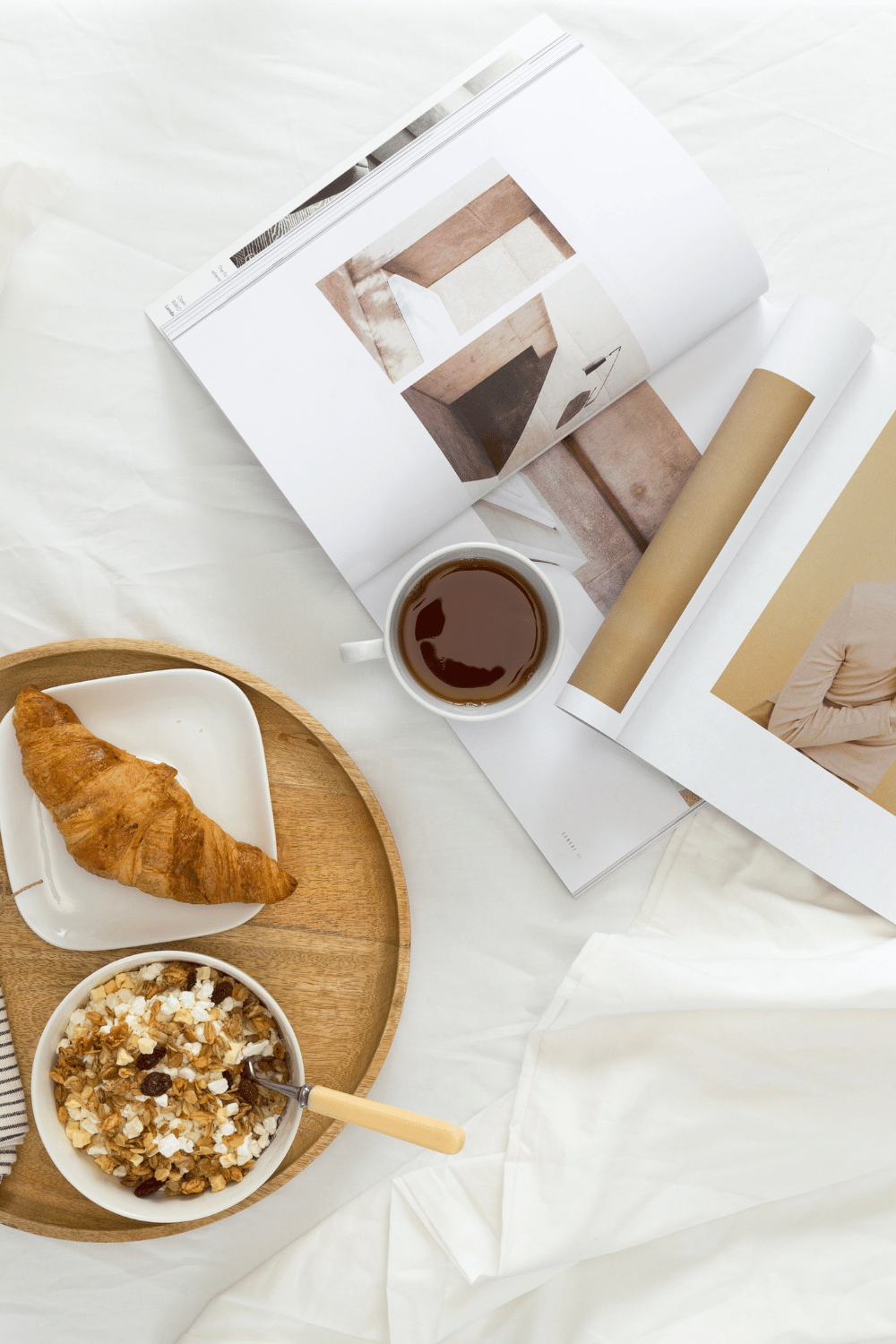 A calm and peaceful morning and breakfast set up with magazines and coffee on white sheets
