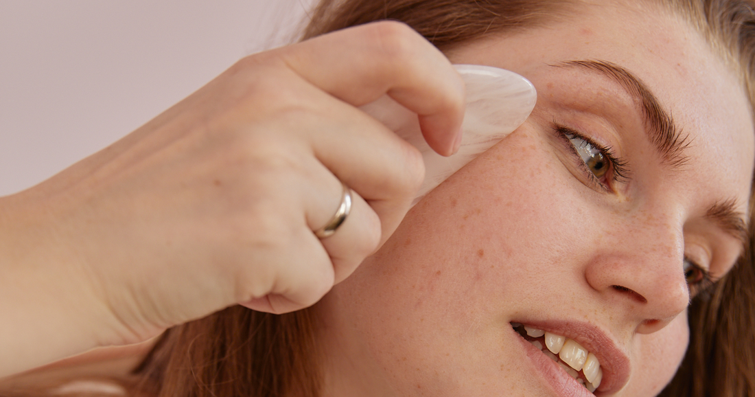 A woman using gua sha tool on her face - Jenny Nordic Skincare