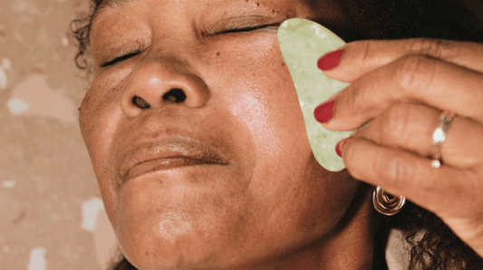 A black woman massaging her face with gua sha stone