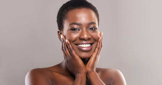 Black woman with a short hait holding hands on her cheeks and smiling