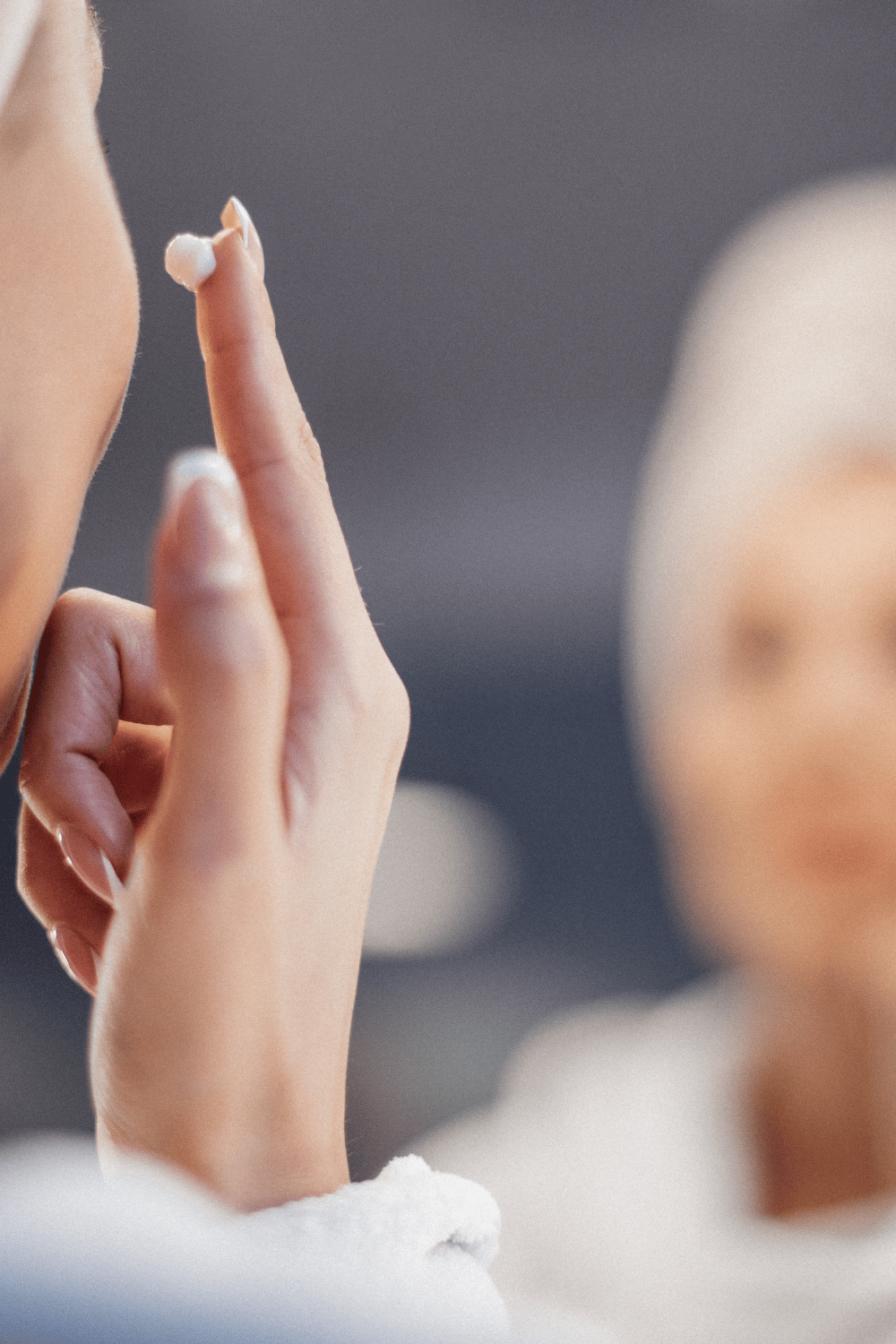 A woman applying face cream on her cheek