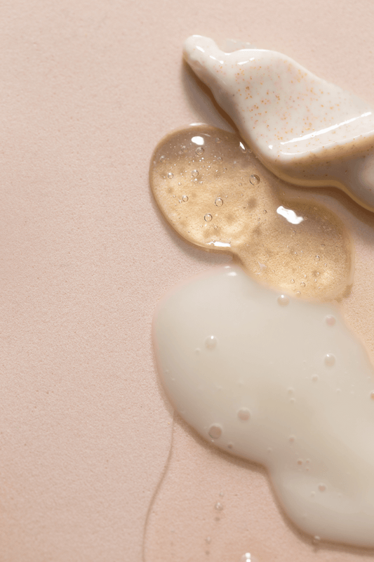 Three different skincare product textures; scrub, gel and foal on a pink surface
