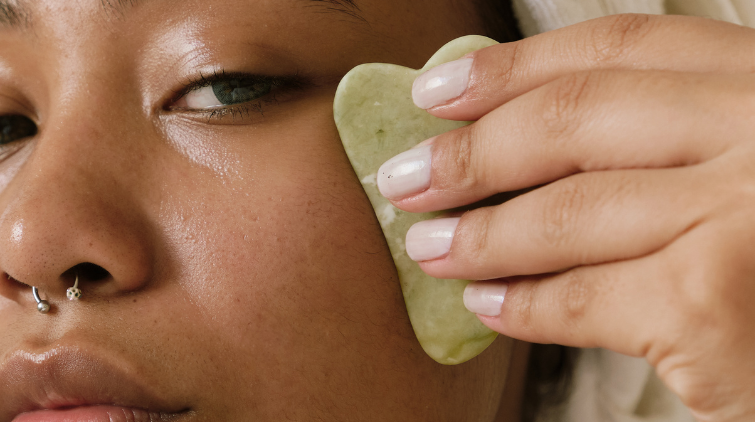 A lady doing gua sha on her face