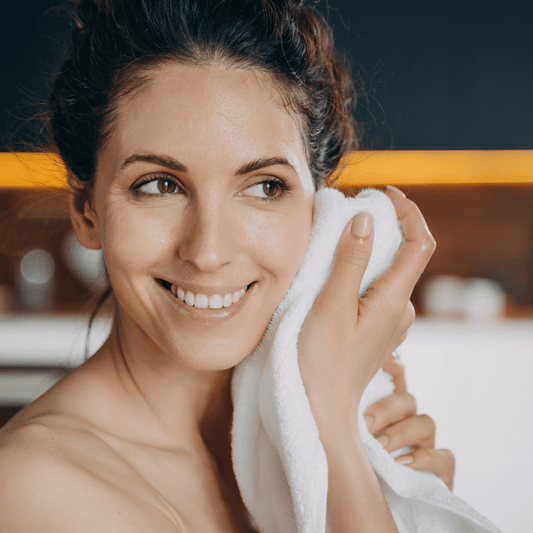 A woman cleansing her face with a towel