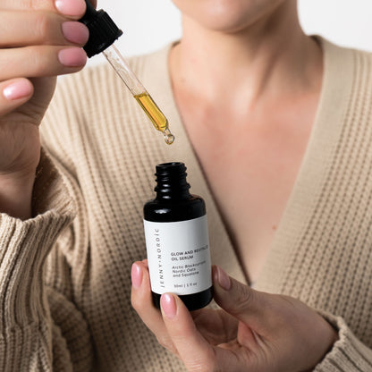 A woman holding an open bottle of Jenny Nordic Skincare Glow & Revitalize Oil Serum